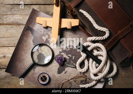Bag with travel equipment, world map, mineral stones and airplane toy on brown wooden background Stock Photo