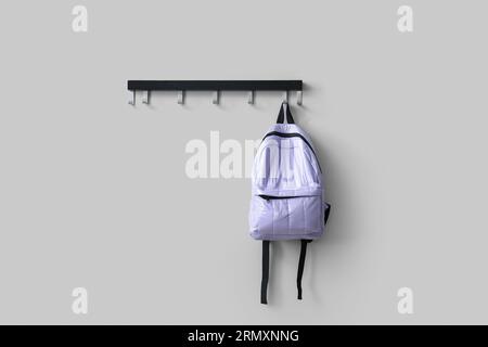Stylish school backpack hanging on white wall in room Stock Photo