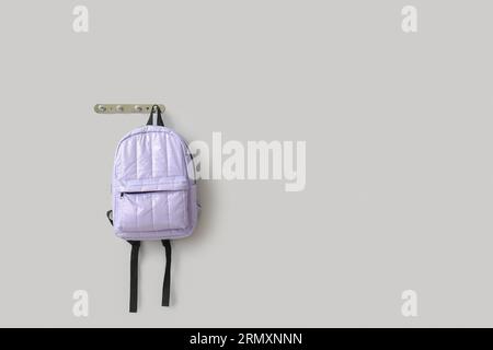 Stylish school backpack hanging on light wall Stock Photo