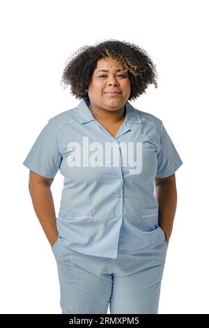 vertical portrait of venezuelan afro latina medical woman, wearing blue uniform, standing smiling and looking at camera on white background Stock Photo