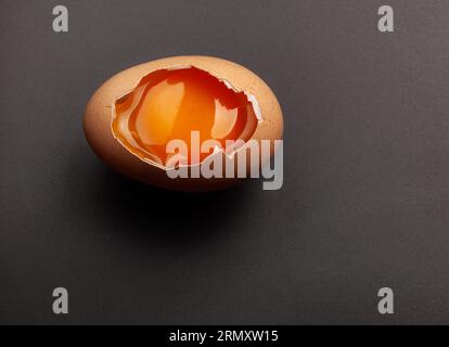 Сhicken egg yolk in the shell on dark grey background Stock Photo