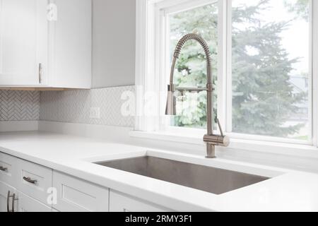 A kitchen faucet detail with a bronze faucet, white marble