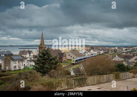 Train driving through the city of Castlerock in Northern Ireland on a cloudy spring day. Commuting through beautiful irish countryside and villages. Stock Photo