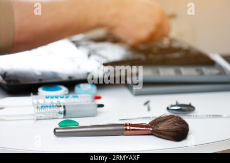 Cleaning brush and dusty laptop cooling fan on white background. Air vent fan for heatsink cooling system for cpu. Fixing overheating. Professional te Stock Photo