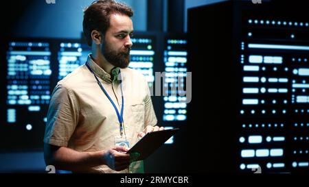 Developer in server room walking through data hardware clusters used for computationally intensive tasks such as scientific simulations or 3D rendering. Programmer doing computing software updates Stock Photo