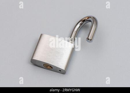 Unlocked silver padlock on the gray background. Stock Photo