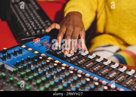 Unrecognizable ethnic female radio host using professional mixing console while working in broadcast studio Stock Photo
