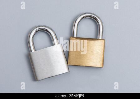 Locked silver and golden padlock on the gray background. Stock Photo