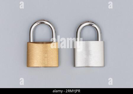 Locked silver and golden padlock on the gray background. Stock Photo