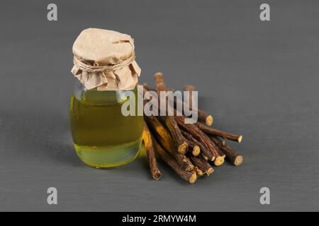Dried sticks of licorice roots and essential oil on grey wooden table Stock Photo