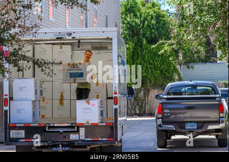 NEW ORLEANS, LA, USA - AUGUST 17, 2023: Man lifts a box in the back of a loaded truck during a move-in to an apartment building in Uptown New Orleans Stock Photo