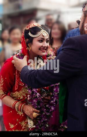 The radiant Nepali bride, draped in a resplendent red saree, warmly welcomes her groom with joyous anticipation of their union, a picture of timeless . Stock Photo