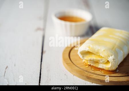 Close up picture of white cream milky kaymak butter roll poured with honey on wooden plate Stock Photo
