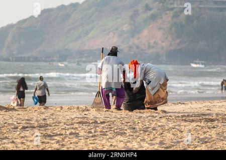 Calangute, Goa, India - January 2023: Two female sanitation workers picking trash on a popular tourist beach in Goa. Stock Photo