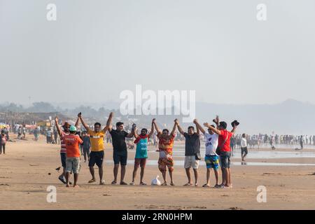 Calangute, Goa, India - January 2023: A large group of Indian men enjoying the beach while dancing together. Stock Photo