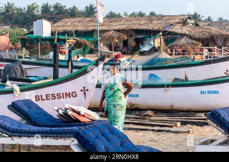 Calangute, Goa, India - January 2023: A female worker at a tourist beach shack standing with a background of fishing boats. Stock Photo