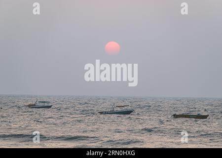 Calangute, Goa, India - January 2023: Sun set above boats sailing in the sea in Goa. Stock Photo