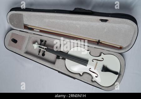 A white violin with a bow lies in a violin case Stock Photo