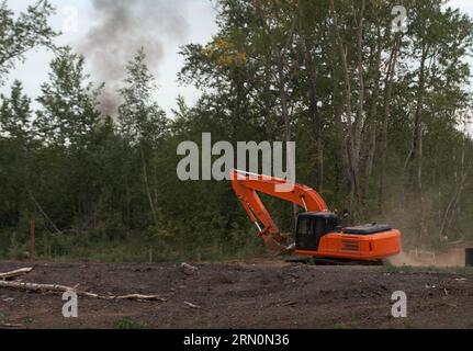 Orange excavator in a cloud of dust works at a construction site Stock Photo