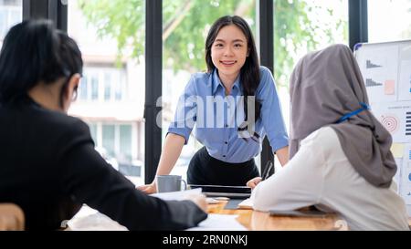 An attractive and confident Asian businesswoman or female manager is leading the meeting with her diverse team. Stock Photo