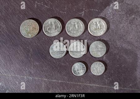 Reverse of nine American coins arranged in a pattern on a grey slate background Stock Photo