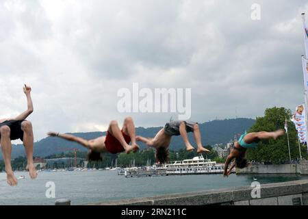 Three young men and one woman are jumping backwards to Lake Zurich. Stock Photo