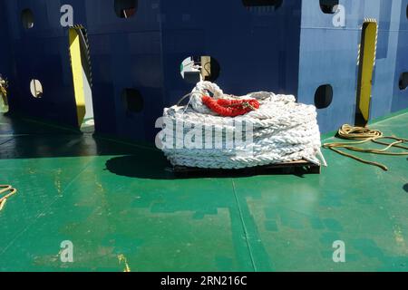 White fibre mooring rope or line rolled up in forward mooring station of container vessel lying in green main deck. Stock Photo