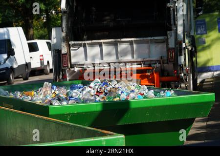 Waste plastic bottles and aluminium cans from beverages are collected in green open containers. Stock Photo