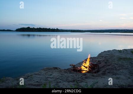 campfire on the lake shore at sunset Stock Photo