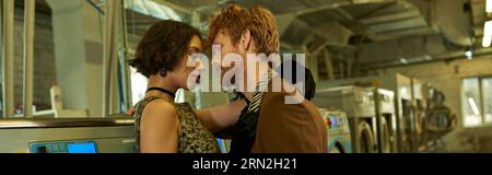 modern and stylish interracial couple kissing near washing machine in coin laundry, banner Stock Photo