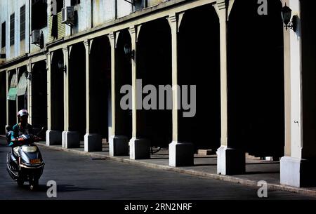 A resident rides past a Qilou building in Chaozhou City, south China s Guangdong Province, Oct. 27, 2014. Qilou buildings, or arcade-houses, were first popular in Europe and was then introduced to the world. China s first Qilou building was built in Guangzhou, capital of south China s Guangdong Province, which is also among the first coastal cities to embrace foreign culture and begin modernization. In the 30s and 40s, the Qilou architecture started to prevail in China s southern parts like Guangdong, Guangxi, Hainan and Fujian, and it gradually became a distinctive architectural feature in th Stock Photo