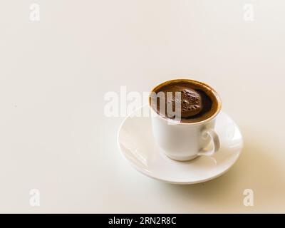 Small white porcelain cup and saucer of hot black brewed turkish coffee, Coffee culture concept. Isolated on white. High quality photo Stock Photo