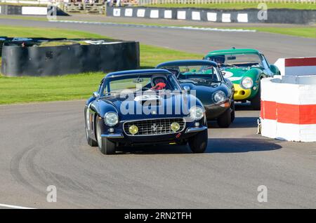 Ferrari 250 GT SWB classic sports car, vintage racing car competing in the RAC Tourist Trophy at the Goodwood Revival historic event, UK. Chasing cars Stock Photo