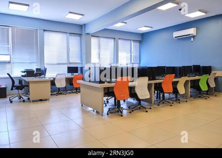 empty computer lab in a university. Computer lab room. room with a lot of computers, desks, chairs, and keyboards. Stock Photo