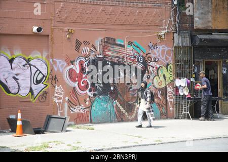 People pass by one of the many Bedford Stuyvesant neighborhood murals that portray African American  creative persons along Fulton Street in Brooklyn, New York. Stock Photo