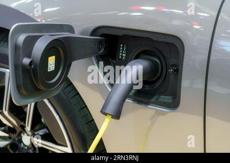 EV car rests at a charging station, power cable connected, embodying