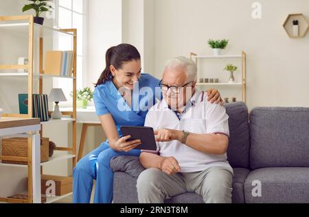Nurse shows older male patient digital tablet with new software application for health monitoring. Stock Photo