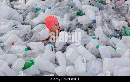 Swimmer swims through many bottles floating on the surface. Stock Photo