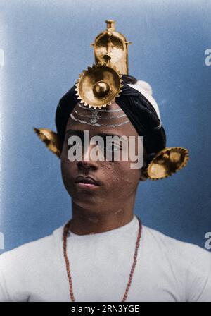 A young Indian man, wearing an elaborate headress and makeup, in a studio setting. Photograph, ca.1900. Photographer: Edwin Nichol Fallaize (1877-1957 Stock Photo