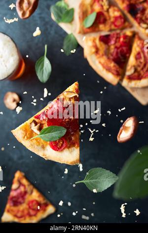 Top view picture of pizza slice falling towards the background. The ingredients are on different heights. There are basil, mushrooms, cheese. Stock Photo