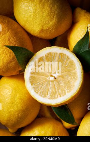 Top view picture of many lemons filling the shot. High contrast vibrant yellow color. Beautiful texture of the citrus. One lemon is sliced. Stock Photo