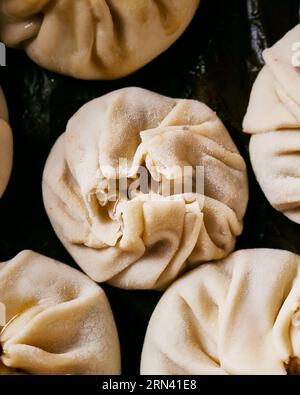 Close up of raw dim sum on a black background. Very detailed as you can see flour particles. Vertical top view image with no people. Stock Photo