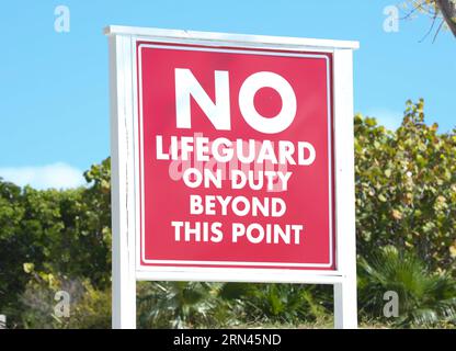 A sign on the beach that says 'No lifeguards on duty'. Stock Photo