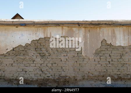 old adobe building wall with peeled off plaster Stock Photo