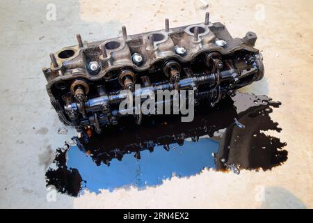 The head of the block of cylinders. The head of the block of cylinders removed from the engine for repair. Parts in engine oil. Car engine repair in Stock Photo