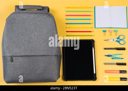 Education, learning, back to school background. Knolling composition with gray backpack and different school stationery supplies on yellow background Stock Photo