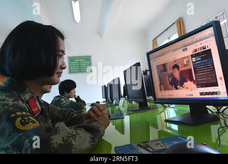 DEHONG, June 24, 2015 -- Zhang Liu watches videos on the internet at the border checkpoint of Mukang in Dehong Dai-Jingpo Autonomous Prefecture, southwest China s Yunnan Province, June 24, 2015. Born in 1995, Zhang Liu became an anti-drug soldier in border checkpoint of Mukang in 2013. Grown up in an affluent family in central China s Hunan Province, Zhang said that being a soldier had always been her dream, which drove her to join the army after graduating from high school. Being a front line anti-drug force, the border checkpoint of Mukang has captured about 100 kilograms of drugs since the Stock Photo