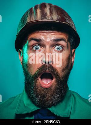 Portrait of surprised industrial worker in protective helmet. Amazed builder, engineer, repairman in safety helmet. Astonished builder or miner in Stock Photo