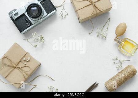 Frame made of camera, tied boxes and dried flower twigs on white grunge background Stock Photo