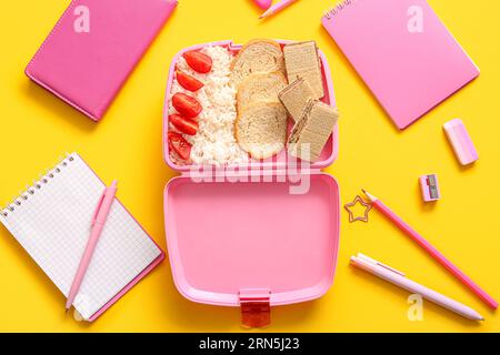 Lunchbox with delicious food and different stationery on yellow background Stock Photo